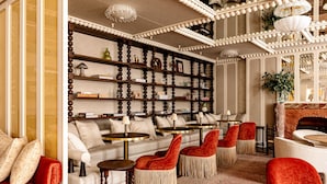A cozy lounge area with a sofa, red chairs, and a bookshelf filled with decorative items. - Chateau des Fleurs Hotel & Spa Paris (Paris)