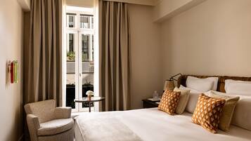 Une chambre d’hôtel avec un lit, une chaise, une petite table et des rideaux.