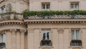 A person reading a book on a balcony with a classical building in the background. - Chateau des Fleurs Hotel & Spa Paris (Paris)