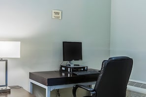 Escritorio de centro de negocios con computadora, silla y señal que indica su ubicación.