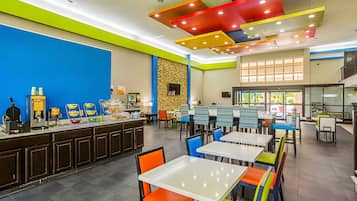 A brightly lit restaurant with a counter, tables, and chairs.