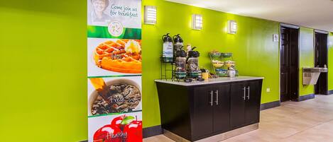 A bright green wall with a breakfast sign, a water dispenser, and a coffee machine.