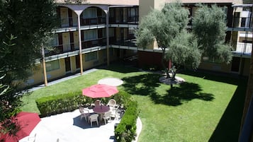 A courtyard with a seating area, a tree, and a building with balconies.