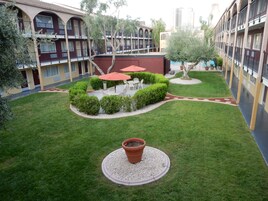 Un patio con una zona de estar central, rodeado de setos podados y una planta en maceta.