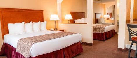 A hotel room with a large bed, two bedside lamps, a mirror, and a chair.