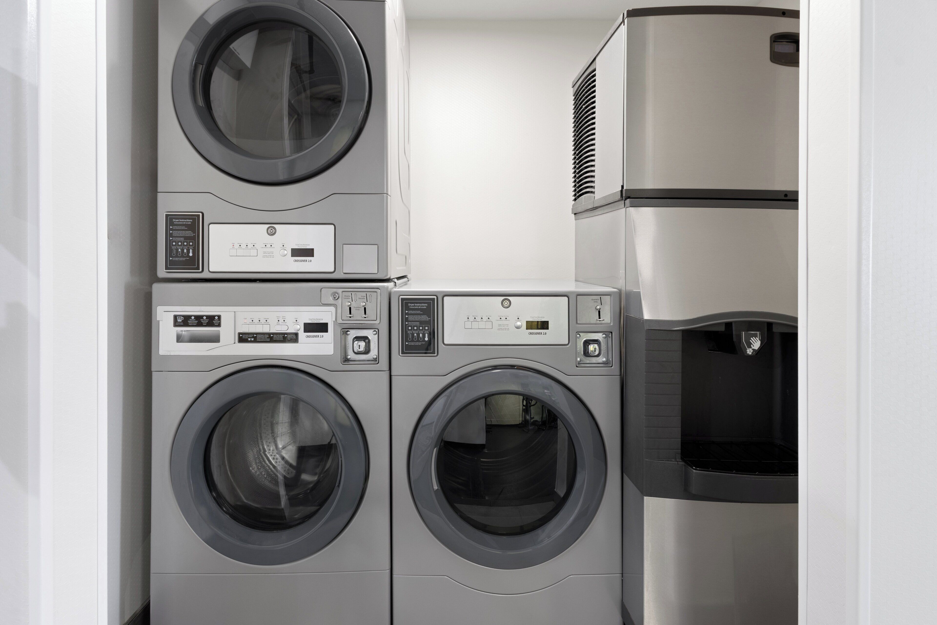 Une buanderie équipée de deux machines à laver à chargement frontal et d’un sèche-linge superposé.