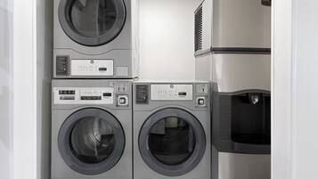 A laundry area with two front-loading washing machines and a stacked dryer.