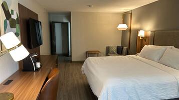 A hotel room with a bed, desk, chair, television, and two bedside lamps.