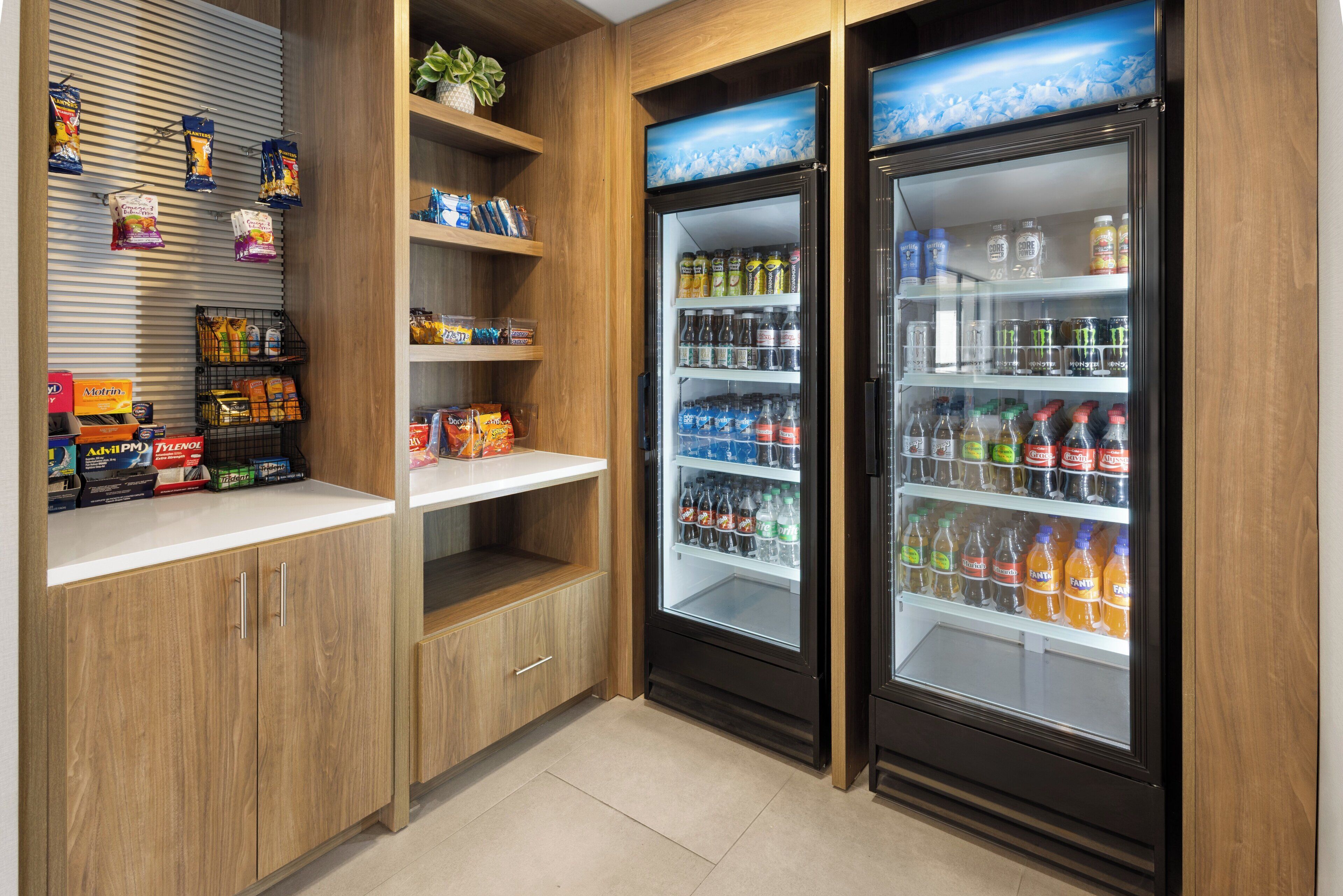 Una kitchenette con armarios de madera, una encimera y dos dispensadores de bebidas repletos de diversas opciones.