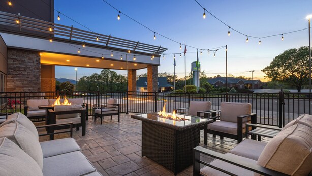 An outdoor patio area with seating and a fire feature, under a covered structure with string lights. - Holiday Inn Roanoke-Tanglewood-Rt 419&i581 by IHG (Roanoke)