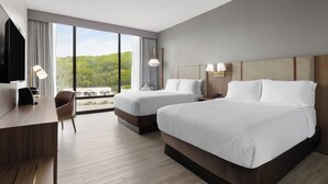 A hotel room with two beds, a desk, a chair, and a large window offering a view of greenery. - Holiday Inn Roanoke-Tanglewood-Rt 419&i581 by IHG (Roanoke)