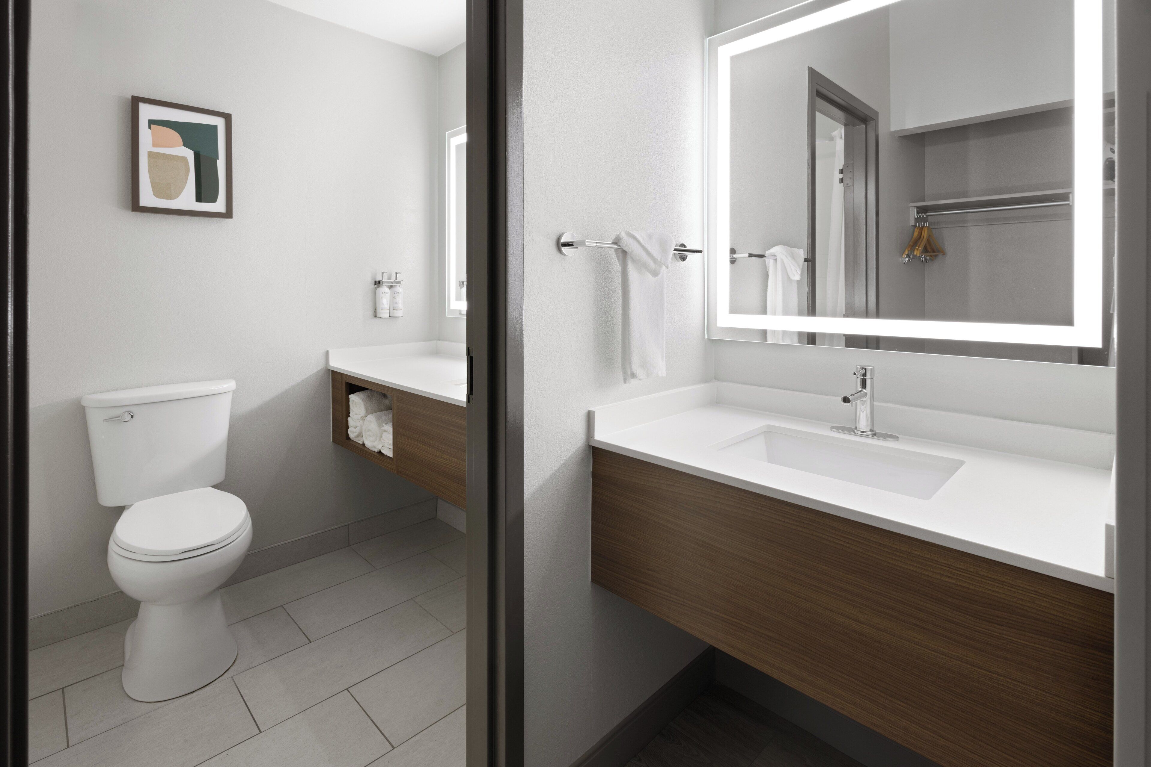 A modern bathroom with a toilet, sink, and mirror.
