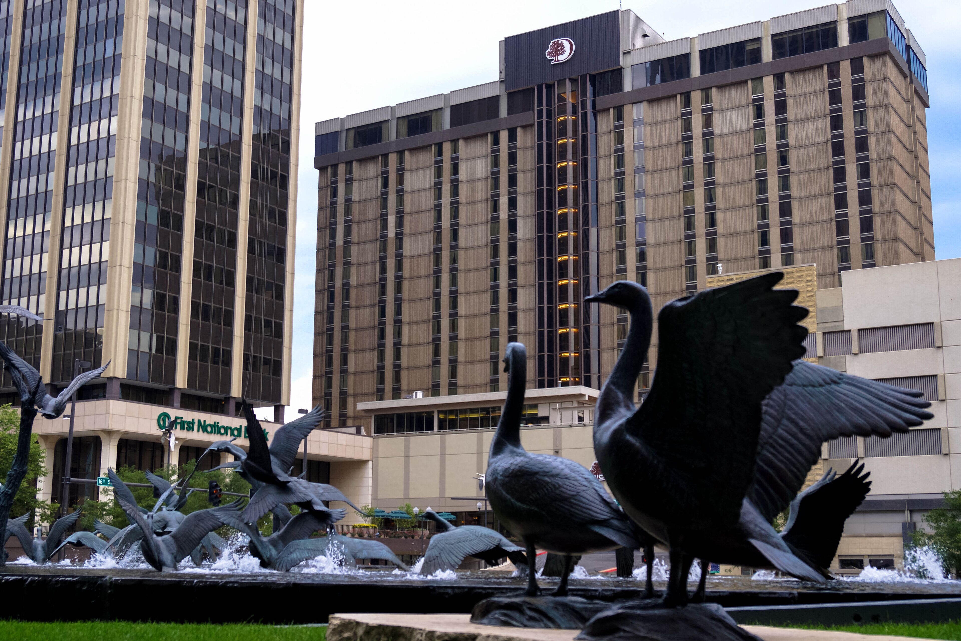Una escultura de aves en vuelo frente a un edificio con un letrero que dice "First National Bank".
