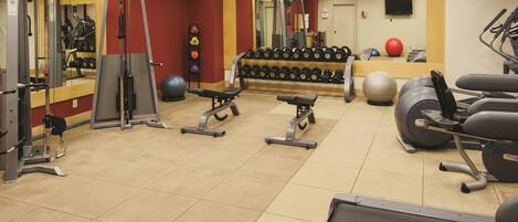 Un gimnasio con diversos equipos de ejercicio, que incluyen máquinas de pesas, pesas libres y máquinas cardiovasculares.