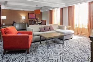 Une chambre d’hôtel comprenant un canapé, un fauteuil, une table basse et un coin repas avec des chaises et une table.