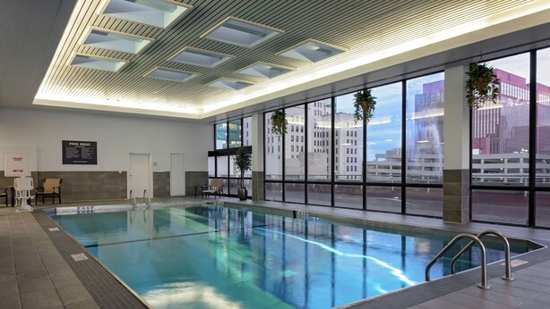 An indoor swimming pool with clear glass walls, a tiled floor, and a ceiling with skylights. - DoubleTree by Hilton Omaha Downtown (Omaha)