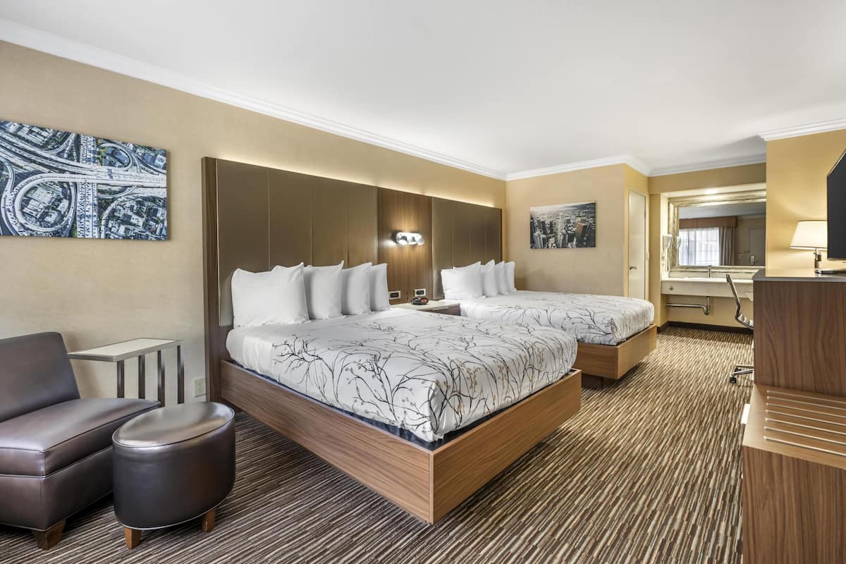 A hotel room with a large bed, two bedside tables, a sofa, and a small ottoman.
