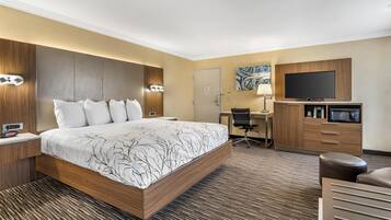 A hotel room with a large bed, a desk with a chair, a television, and a microwave.