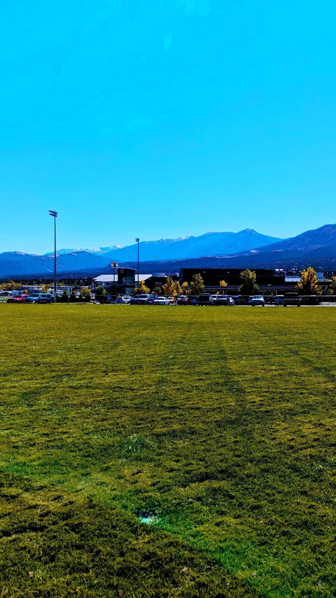 A parking lot with a building in the background and mountains in the distance.