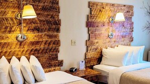 A hotel room with two beds, a wooden headboard, bedside lamps, and a nightstand with a clock and a menu. - Browns Canyon Inn (Salida)