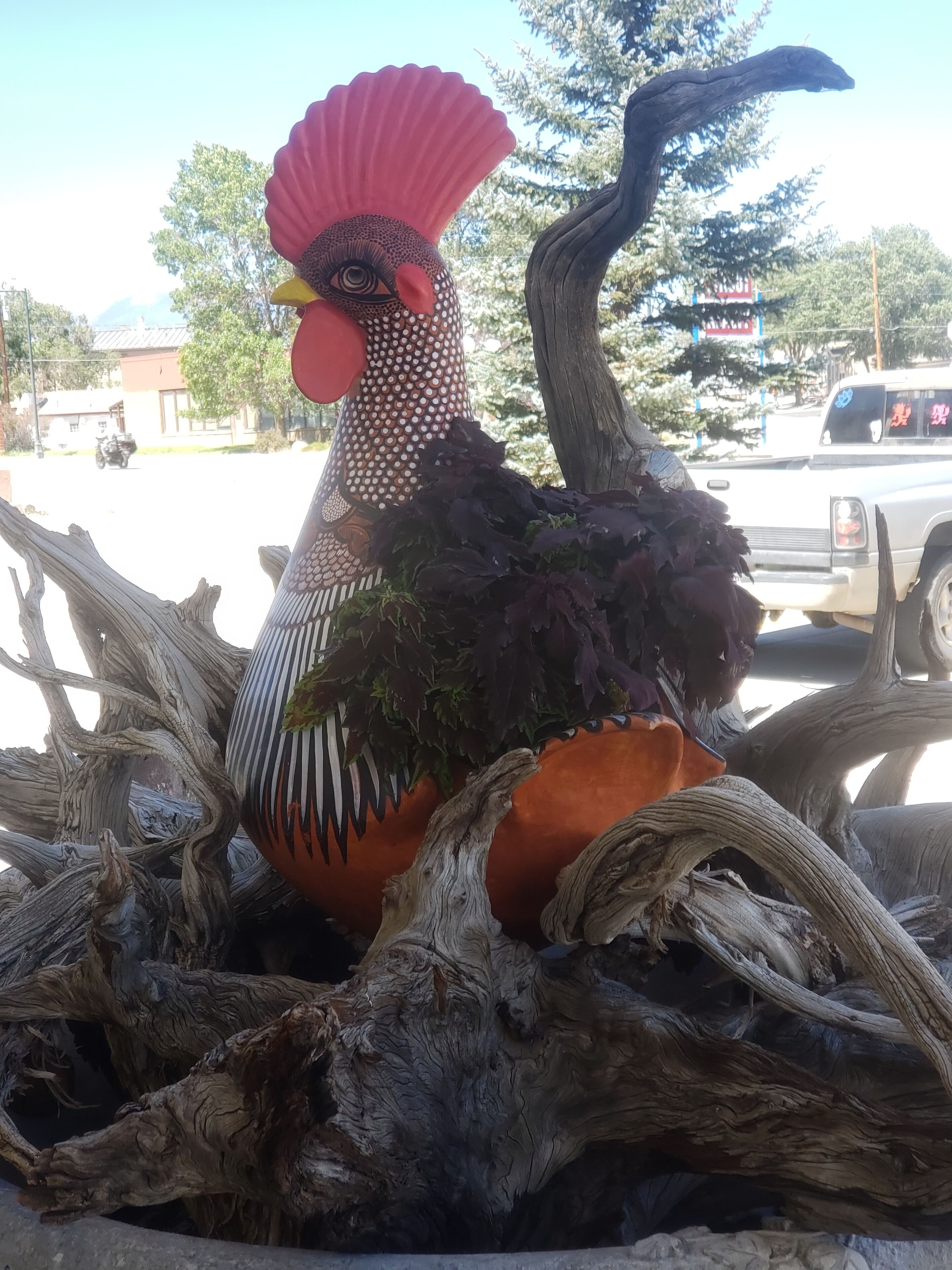 Una escultura decorativa de gallo rodeado de ramas retorcidas.