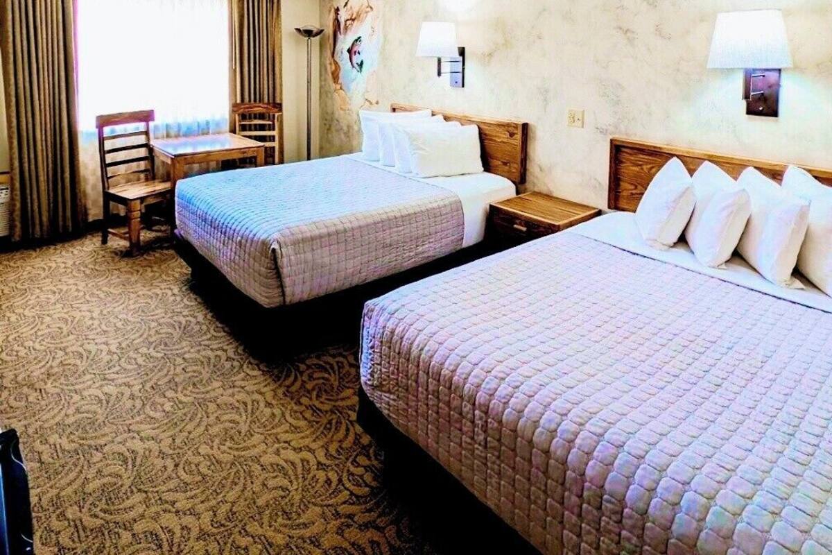 A hotel room with two beds, a desk, and a chair.