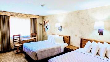 A hotel room with two beds, a desk, and a chair.