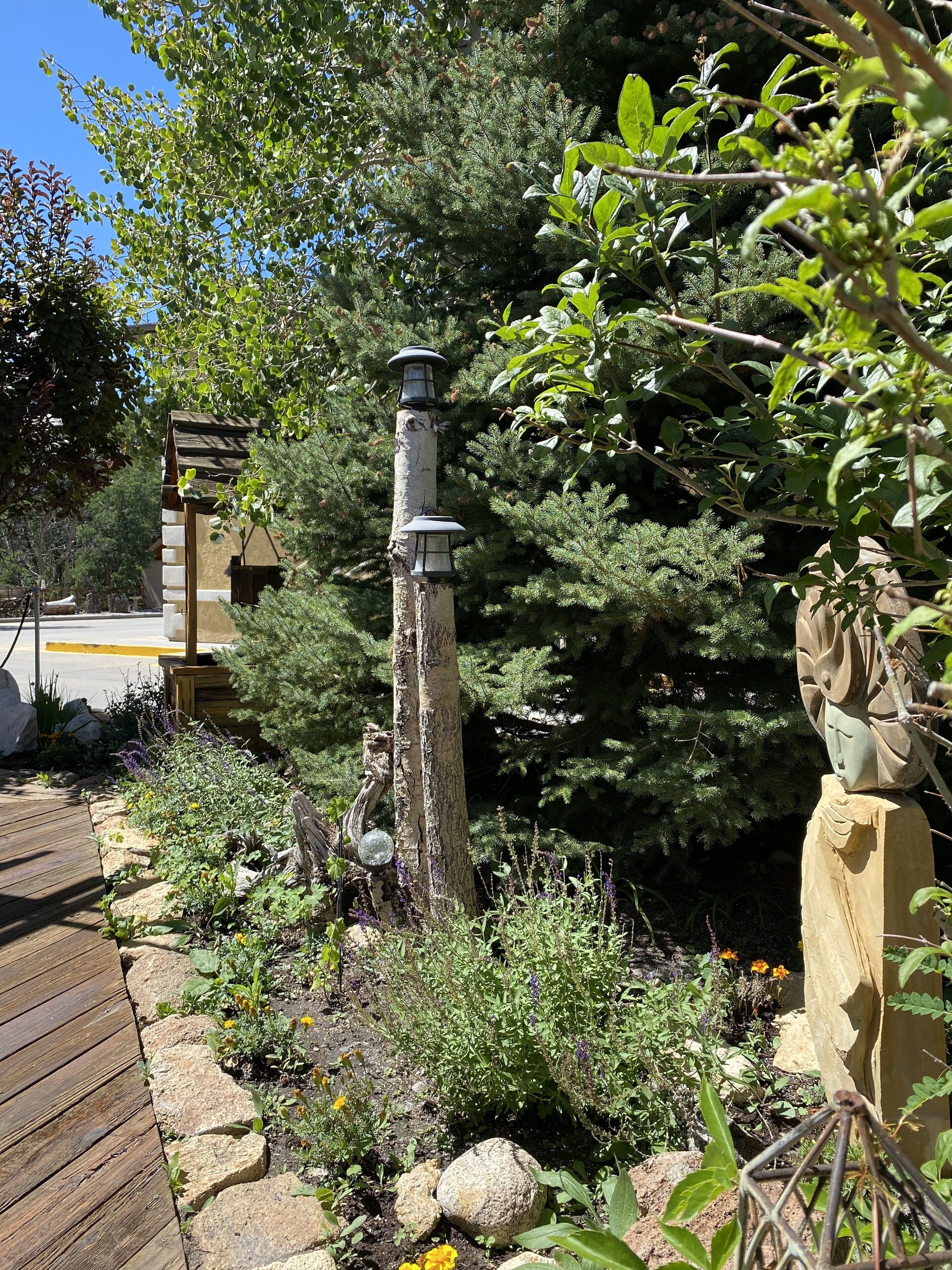 A garden with a wooden deck, a stone wall, and a statue.