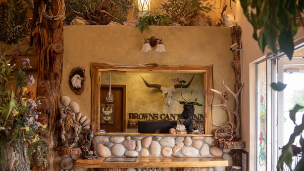 A reception desk with a stone and wood design, a mirror, and a sign that reads "Browns Canyon Inn". - Browns Canyon Inn (Salida)