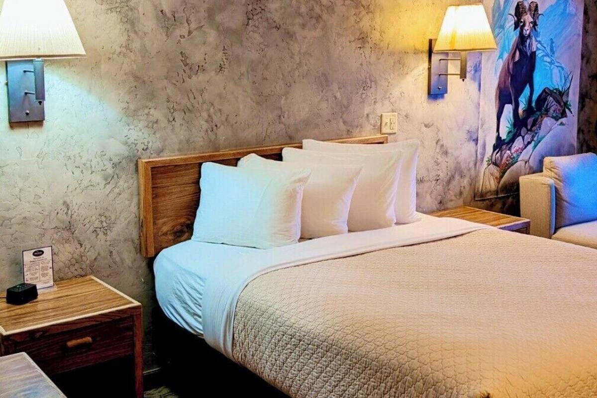 A hotel room with a large bed, two bedside lamps, a nightstand, and a painting on the wall.