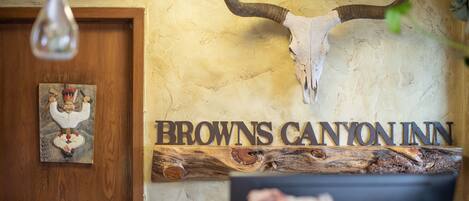A reception desk with a large sign reading "Browns Canyon Inn" and a mounted cow skull above it.