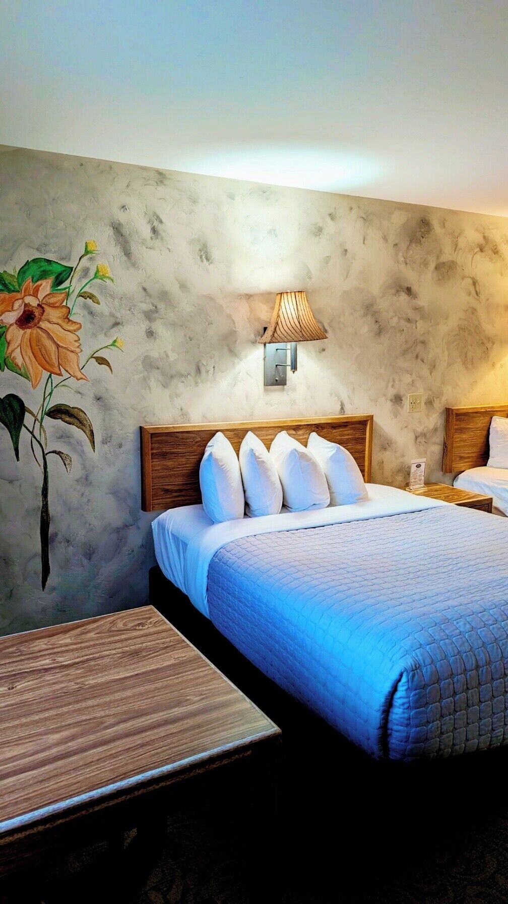 Una camera d'albergo con un letto, un comodino, una lampada e un quadro appeso al muro.