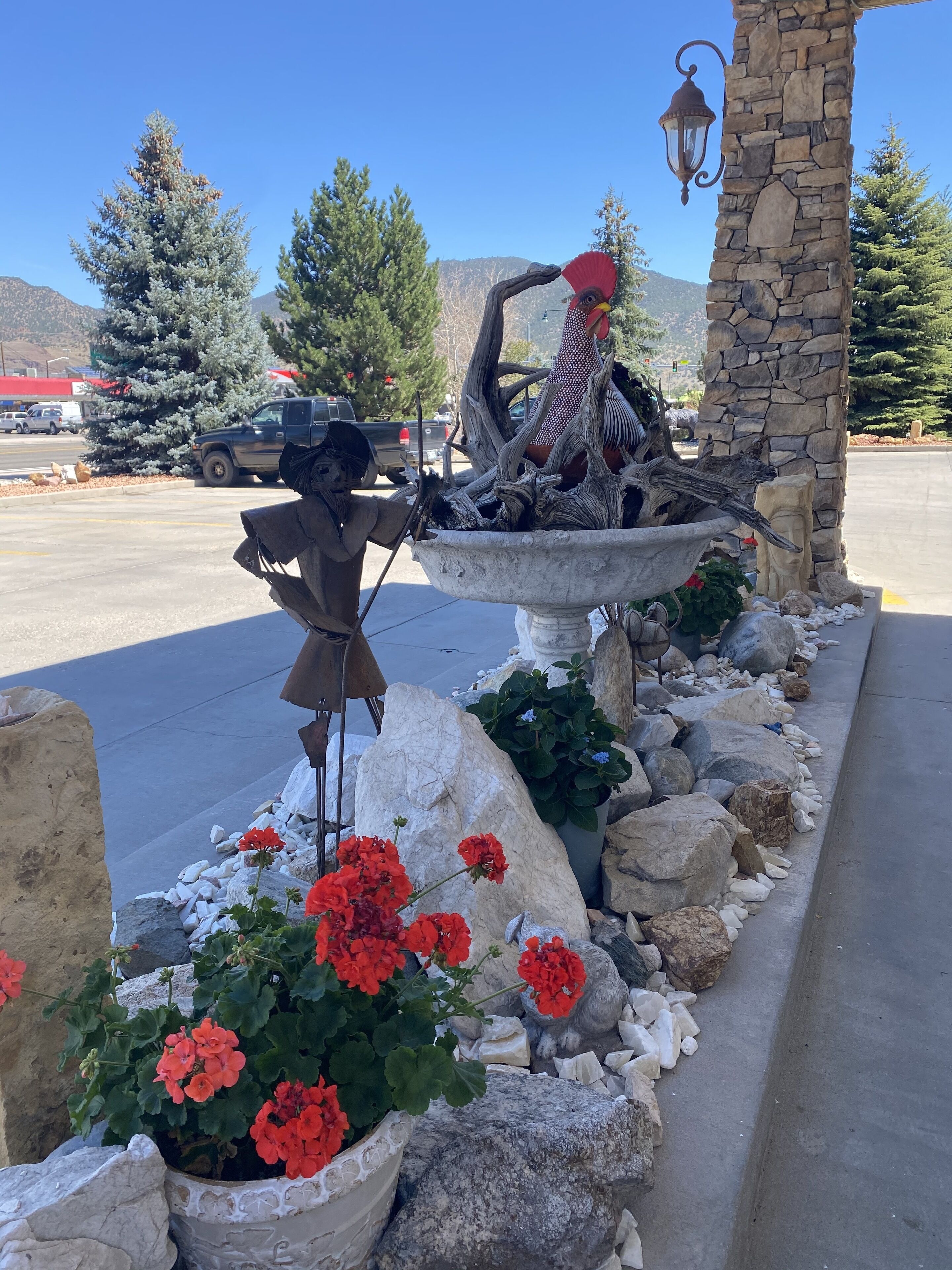 Un espace extérieur décoratif agrémenté d’un pilier en pierre, d’une sculpture d’oiseau et d  ’un abreuvoir à oiseaux.