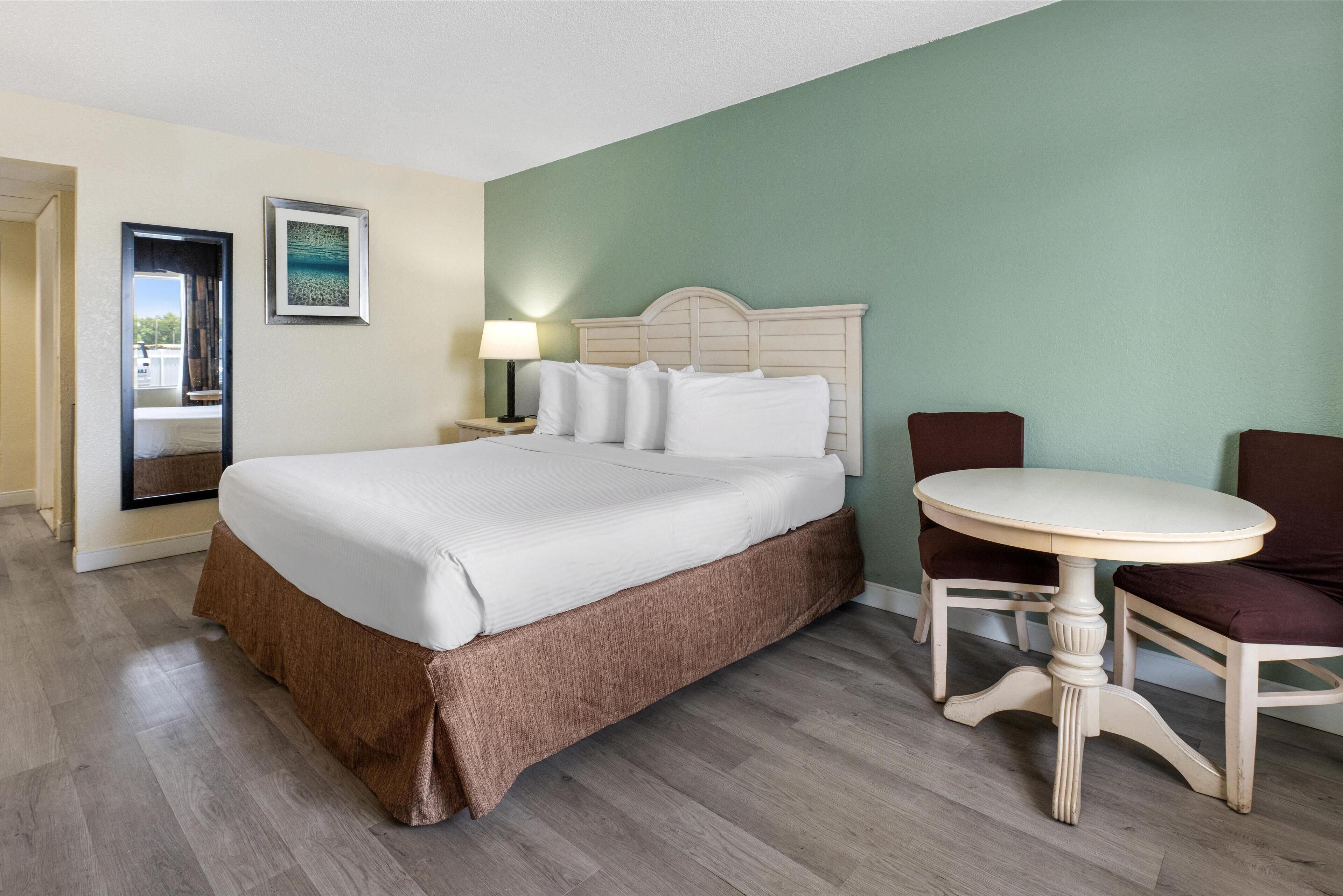 Une chambre d’hôtel avec un grand lit, une table ronde et une chaise.
