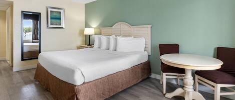 A hotel room with a large bed, a round table, and a chair.