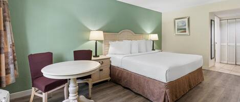 A hotel room with a bed, a round table, two chairs, a nightstand, and a lamp.