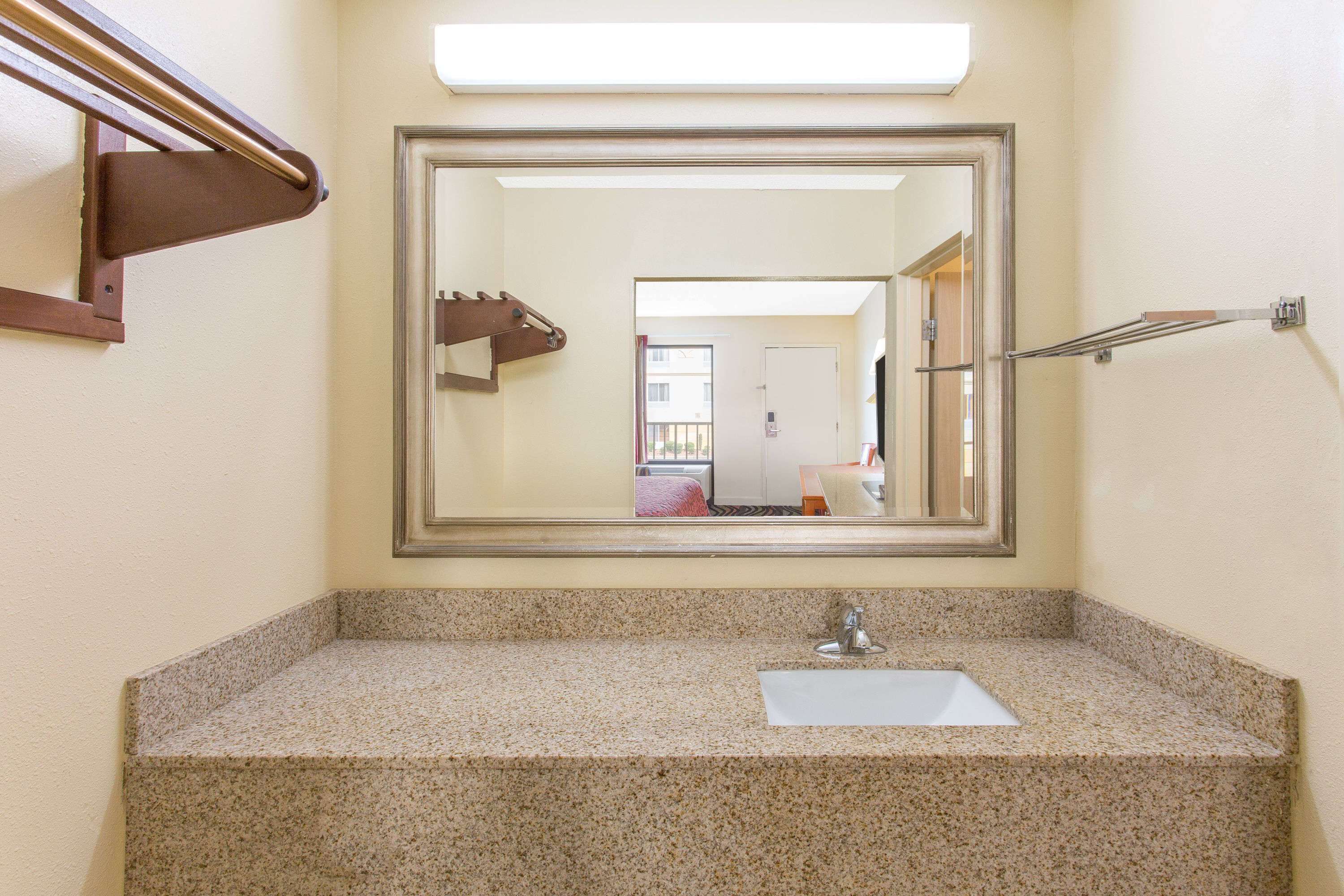 A bathroom with a granite countertop, a white sink, and a large mirror.