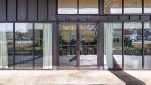 A building with large glass doors and windows, reflecting outdoor scenery. - Days Inn by Wyndham Florence/I-95 North (Florence)