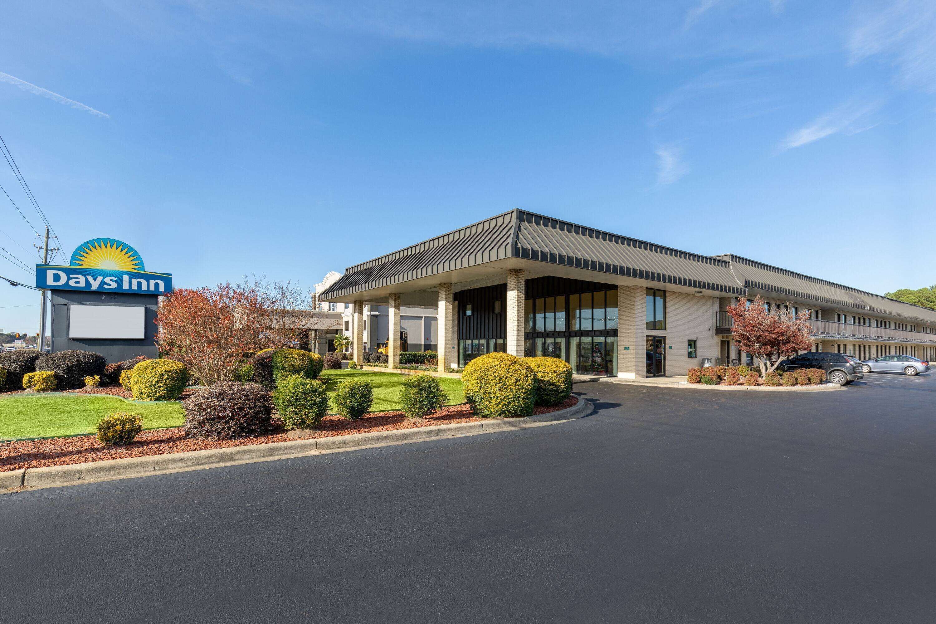 A Days Inn hotel with a modern design, featuring a large sign, a covered entrance, and well-maintained landscaping.