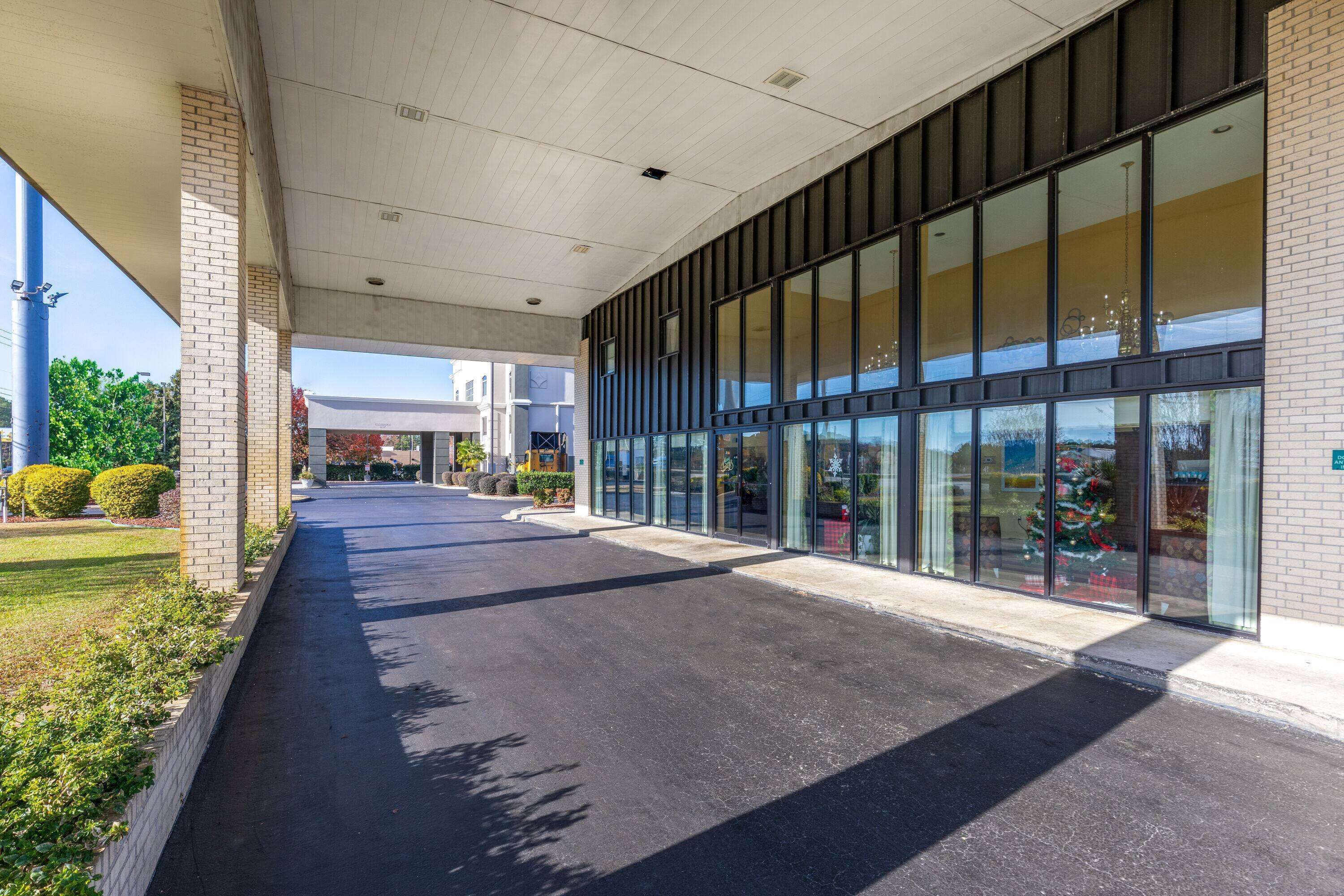 A covered walkway leading to a building with large windows and a brick facade.