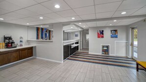 A modern hotel lobby with a wooden counter, a coffee station, and a colorful striped rug. - Motel 6 Carlisle, PA - Cumberland Valley (Carlisle)