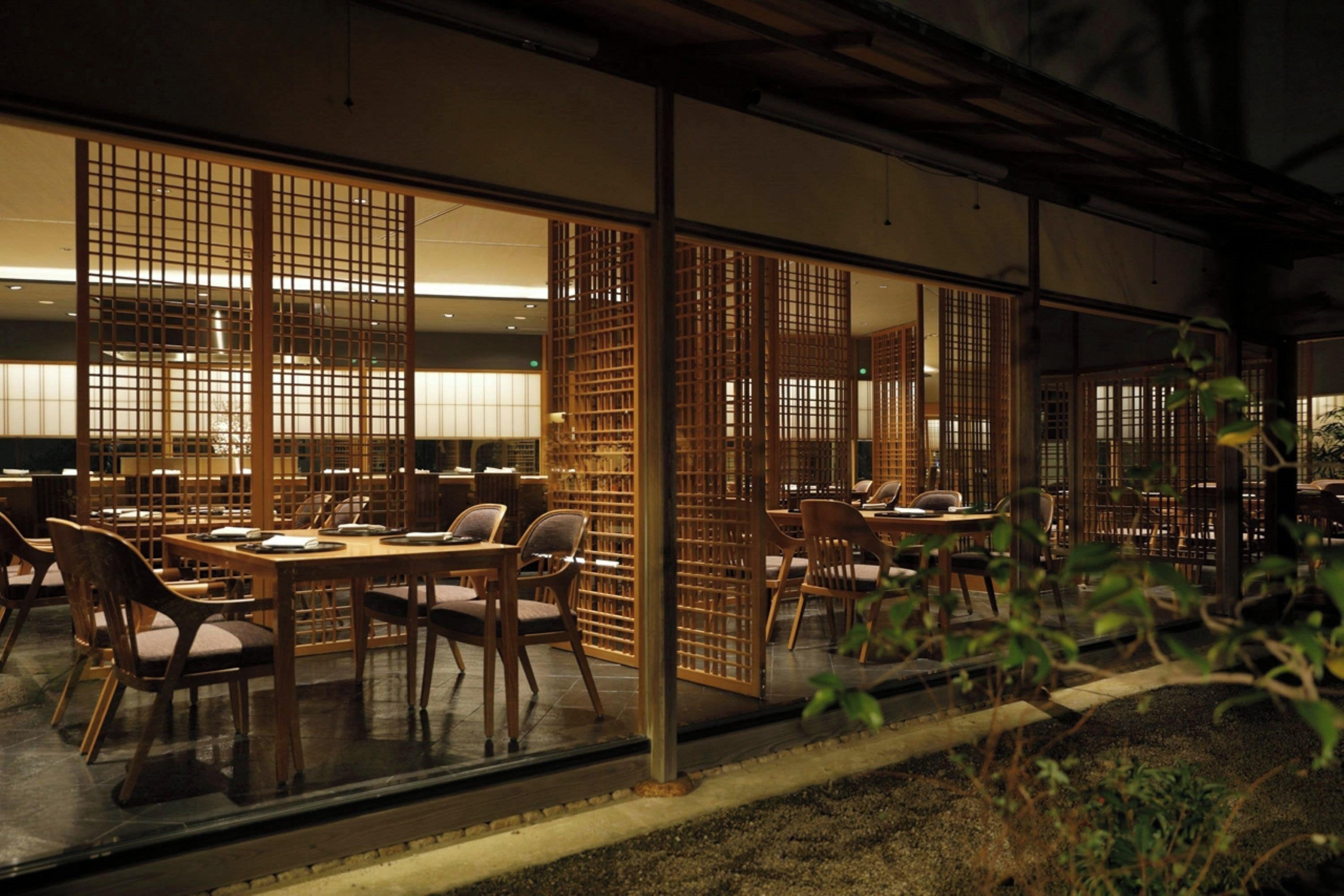 Un restaurante con separadores de madera, mesas y sillas.