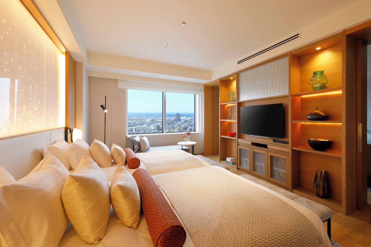 A modern hotel room with a large bed, a television, and a city view.