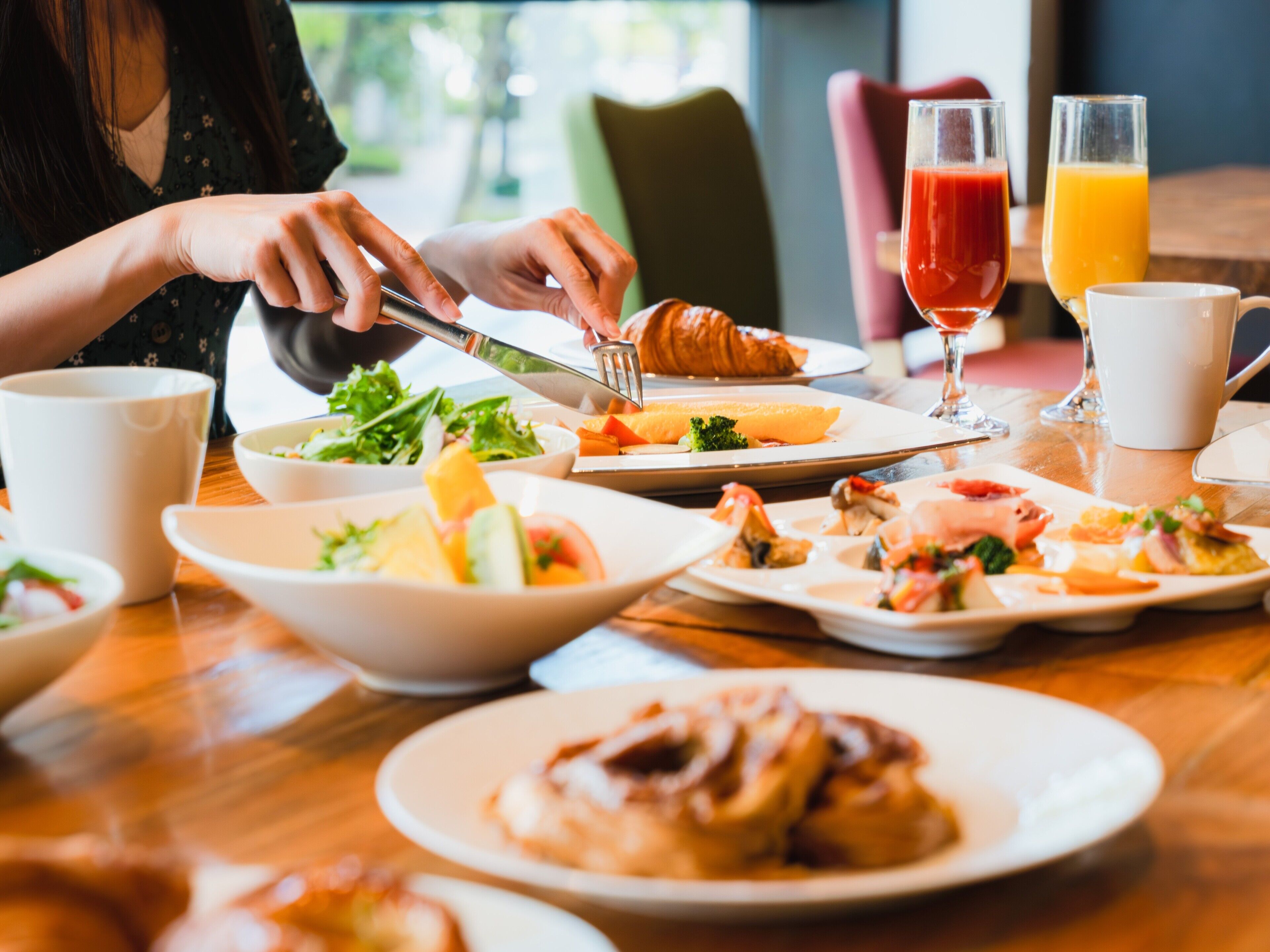 A breakfast setting with various dishes, including croissants and a salad, on a wooden table.