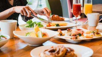 A breakfast setting with various dishes, including croissants and a salad, on a wooden table.