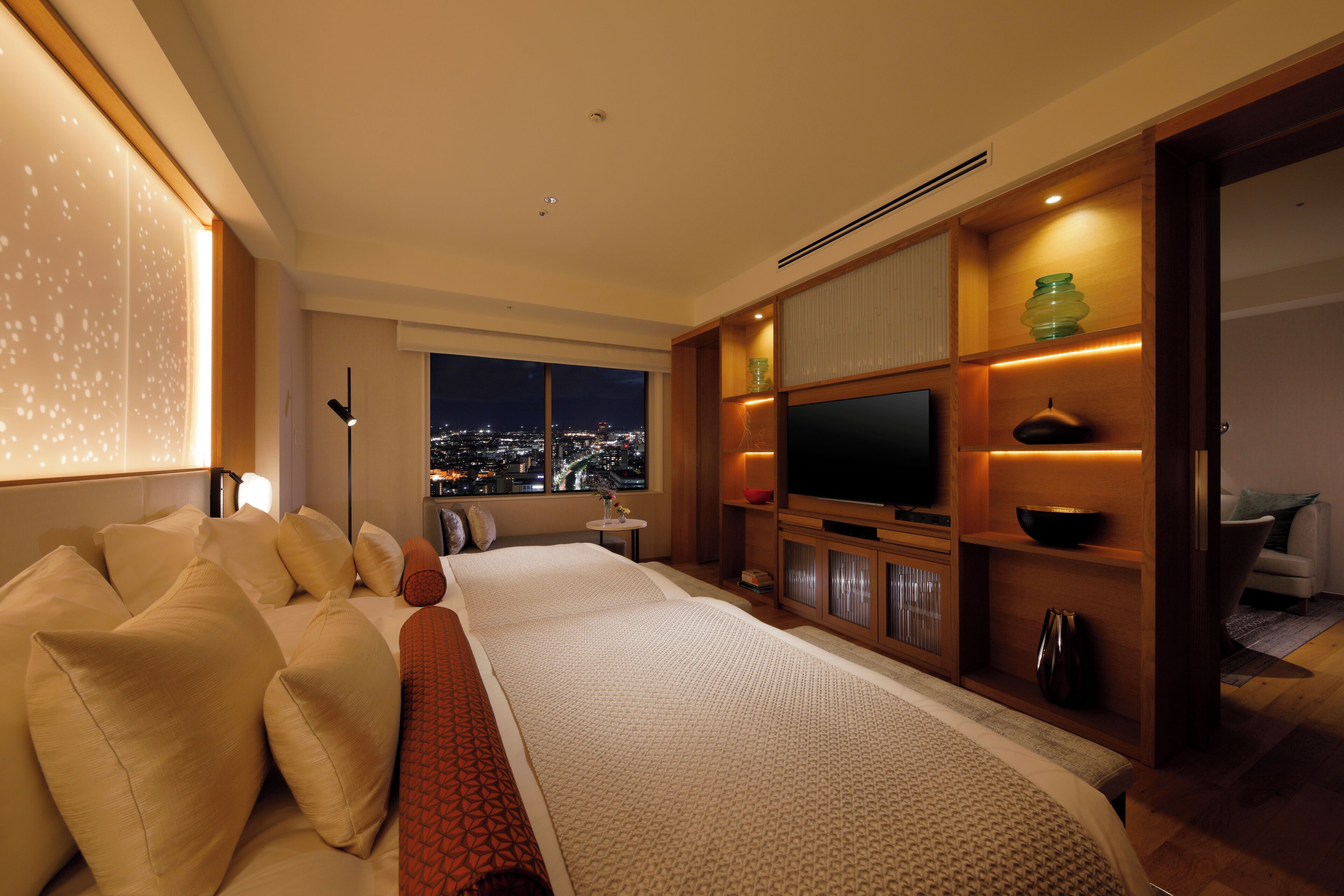 Een moderne hotelkamer met een groot bed, een televisie en uitzicht op de stad.