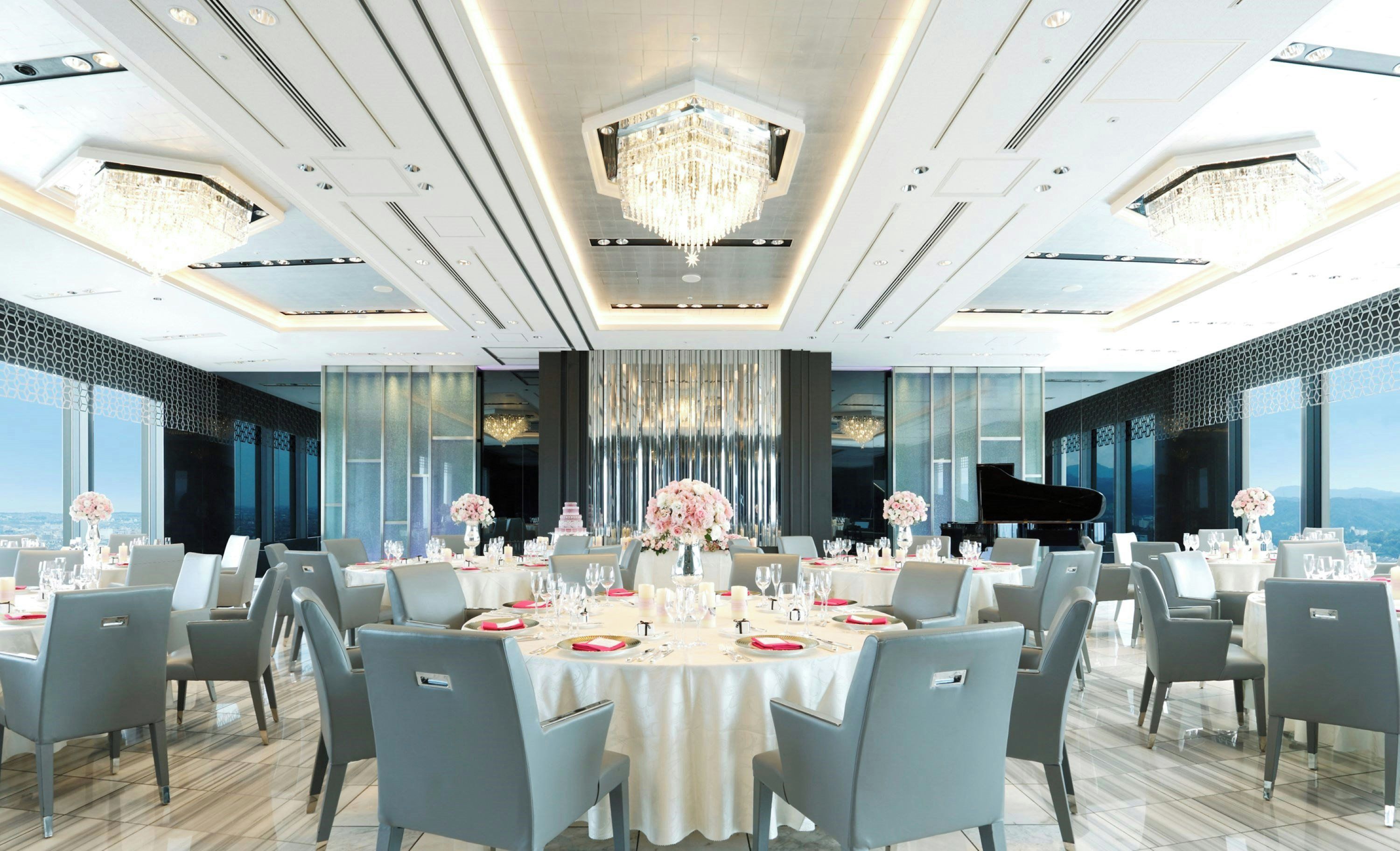 A spacious dining area with round tables, grey chairs, and a grand piano.
