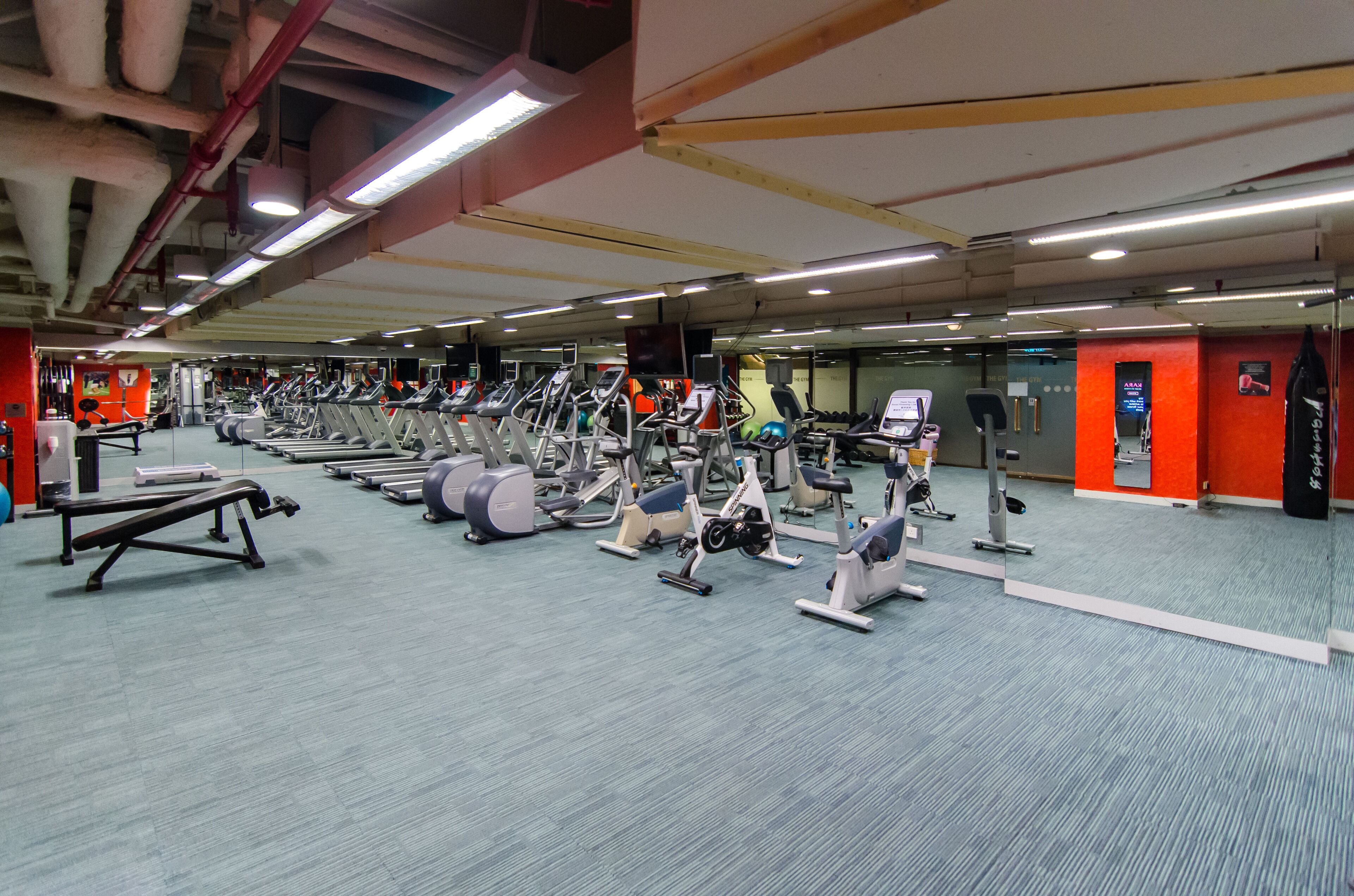 Et fitnesscenter med forskellig træningsudstyr, herunder løbebånd, spinningcykler og styrkemaskiner.