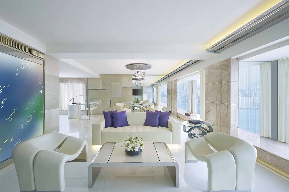 Una sala de estar moderna con un sofá, dos sillones, una mesa de centro y un ventanal con vistas a la ciudad.