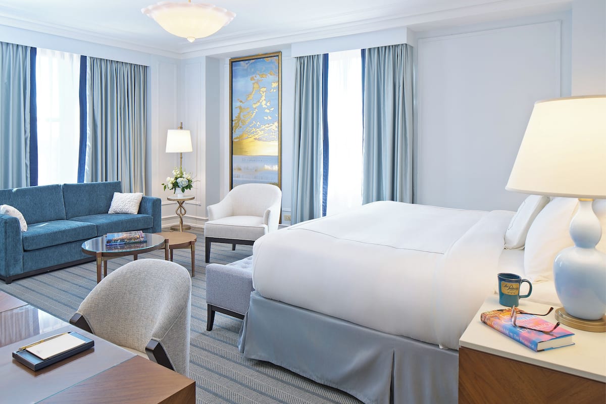 Ein Hotelzimmer mit einem großen Bett, einer Couch, einem Sessel, einem Schreibtisch und einer Lampe.